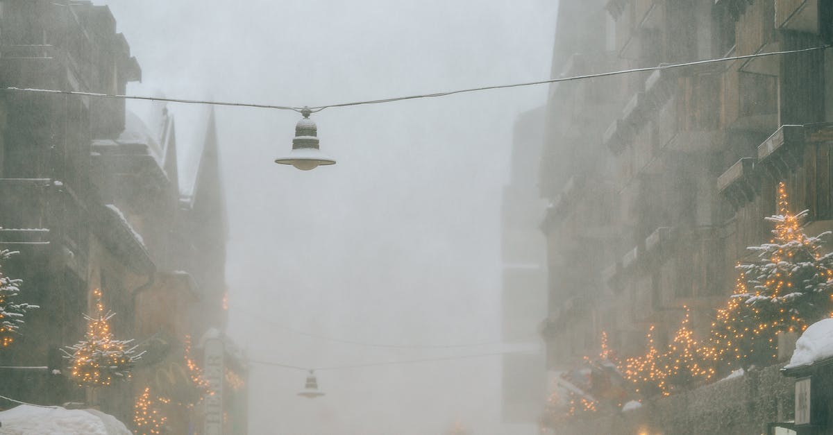 Cool weather destinations in Europe in August [closed] - Modern frozen city street with overhanging streetlamps covered with snow on gloomy foggy winter day