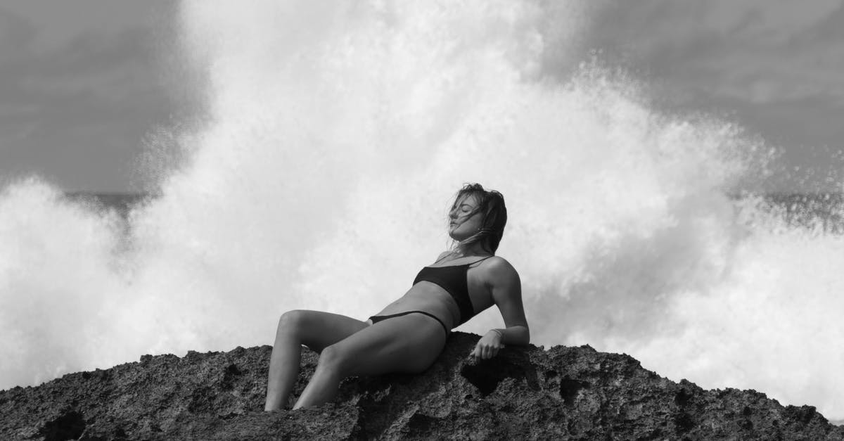 Copenhagen to Odense day trip [closed] - Black and white of relaxed cheerful young female with eyes closed resting on rough cliff on gray cloudy nasty day