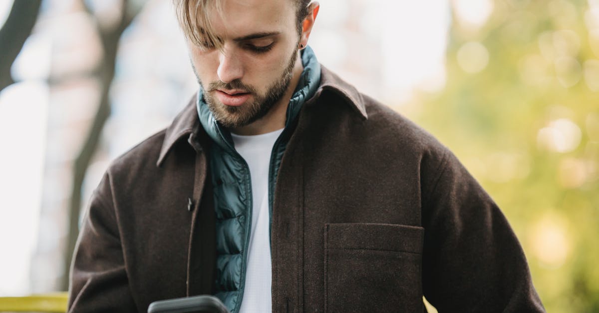 Cost for US cell phone users to receive international calls - Young hipster looking at smartphone screen in park