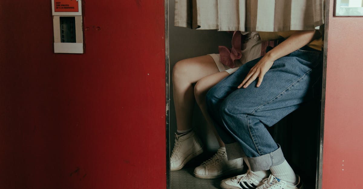 Costume photo booth in San Francisco - Woman in Blue Denim Jeans and White and Black Adidas Sneakers Sitting on Black Floor