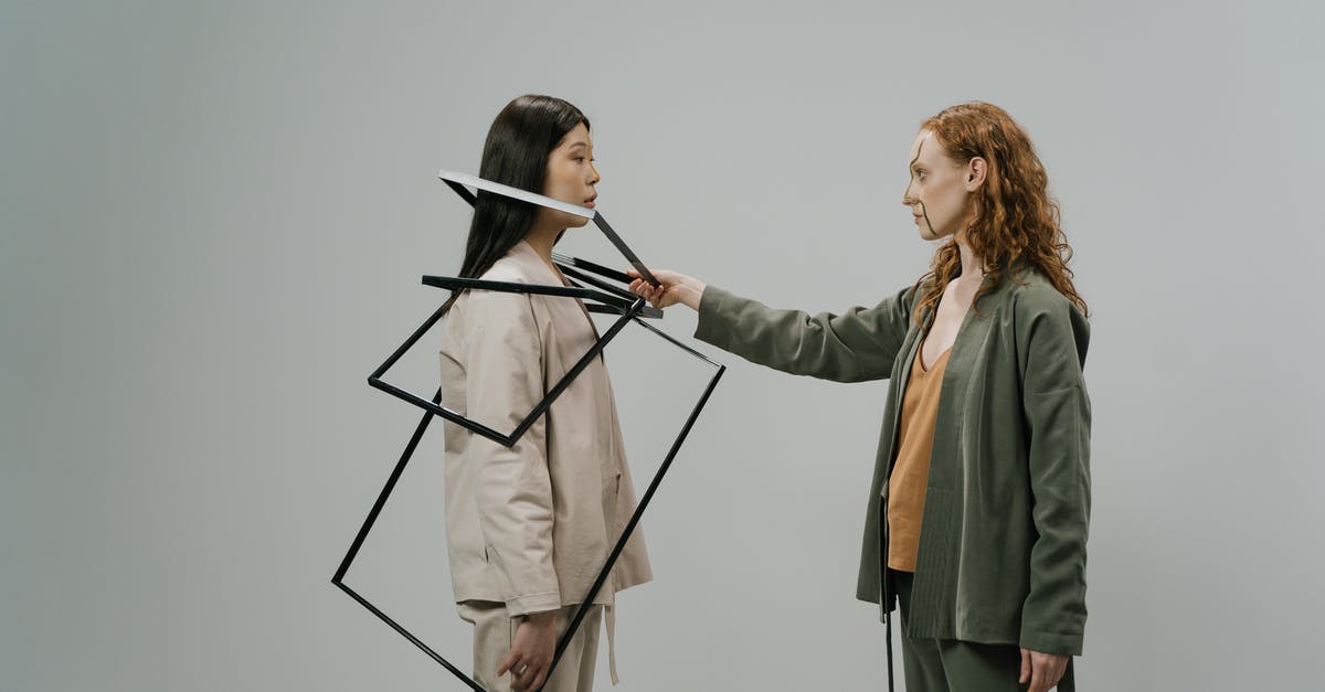 Costume photo booth in San Francisco - Young female model in green costume and beige top putting empty photo frames on shoulders of other female model wearing light beige jacket and trousers