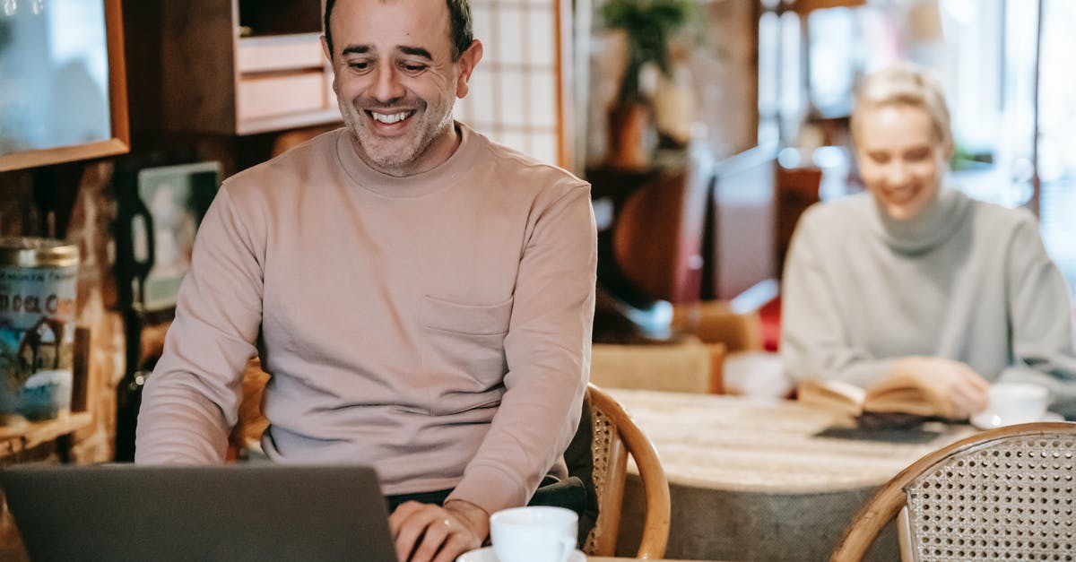 Cover letter for spouse travelling with husband on business visa - Cheerful middle aged ethnic man smiling while working remotely on laptop near positive wife reading book and drinking coffee