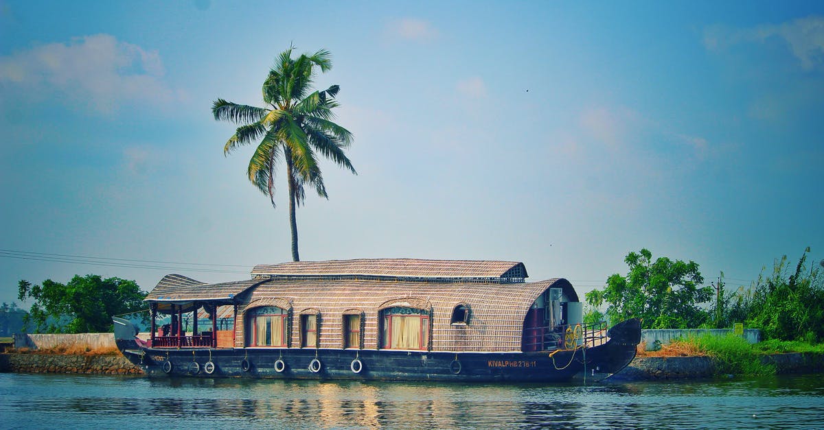 Coverage of unusual activities with travel insurance - Picturesque view of river with green palms on bank and shabby wooden boathouse under blue sky in tropical countryside