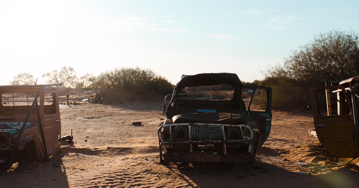 Crashing a rental car abroad - Rusty broken cars placed on sand