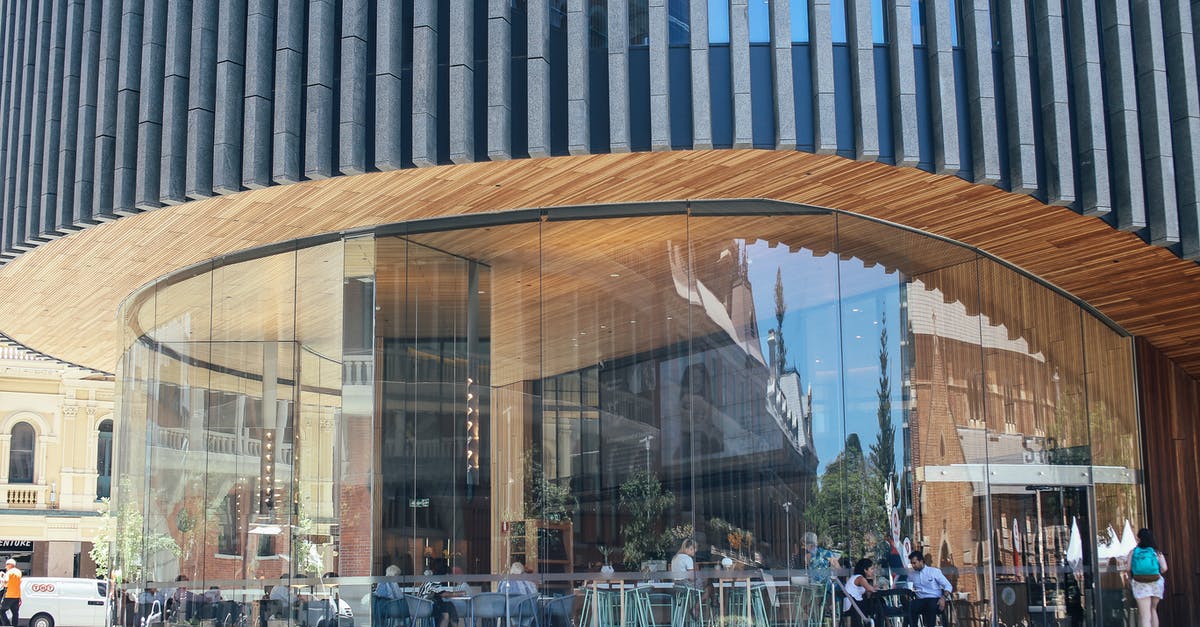 Creative ways to explore a new city [closed] - Facade of modern round shaped futuristic building with contemporary restaurant and glass wall with reflection located on street in city