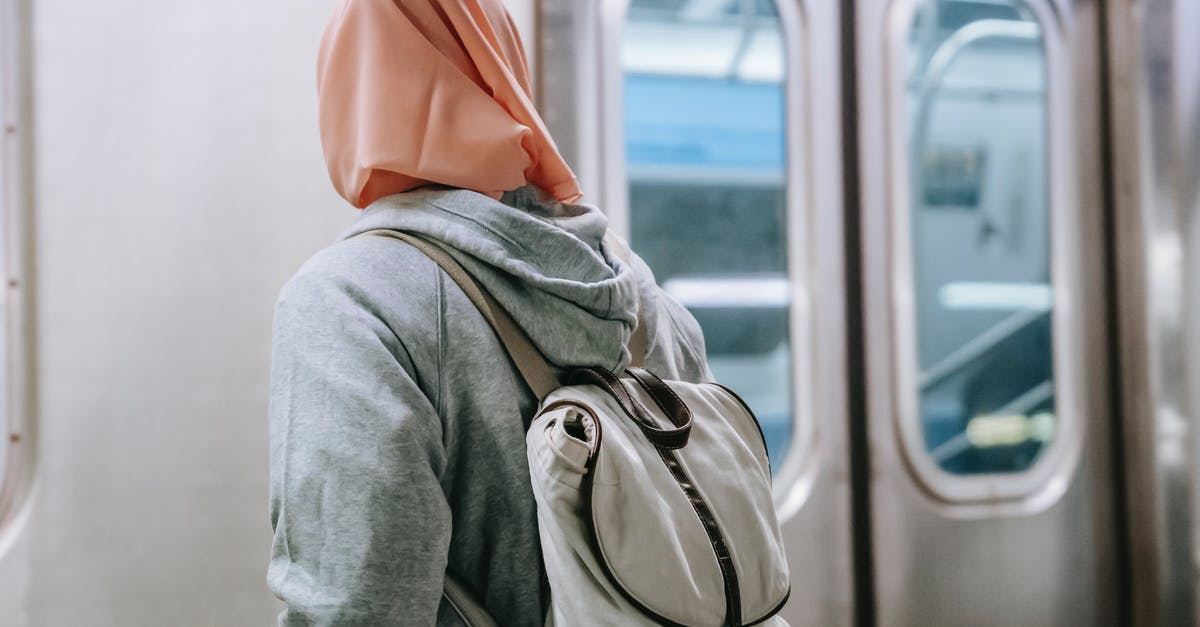 Croatian citizen traveling thru Schengen with non-Croatian spouse - Back view of faceless Muslim woman in casual outfit with backpack and hijab standing near train in metro station