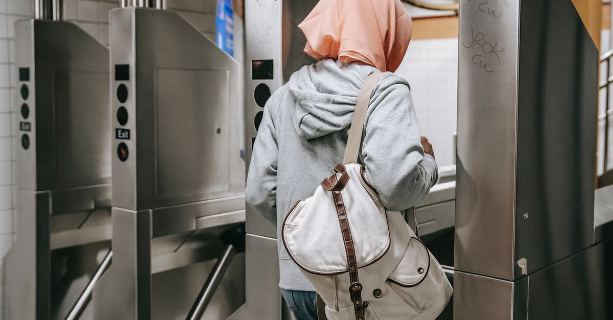 Croatian citizen traveling thru Schengen with non-Croatian spouse - Back view of unrecognizable Muslim woman in casual clothes with backpack and hijab walking through turnstile in metro