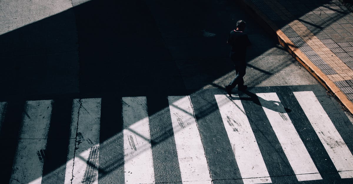 Cross mark on a visa stamp - Bahamas - From above full body of anonymous man in shadow strolling on crosswalk of road in sunny day