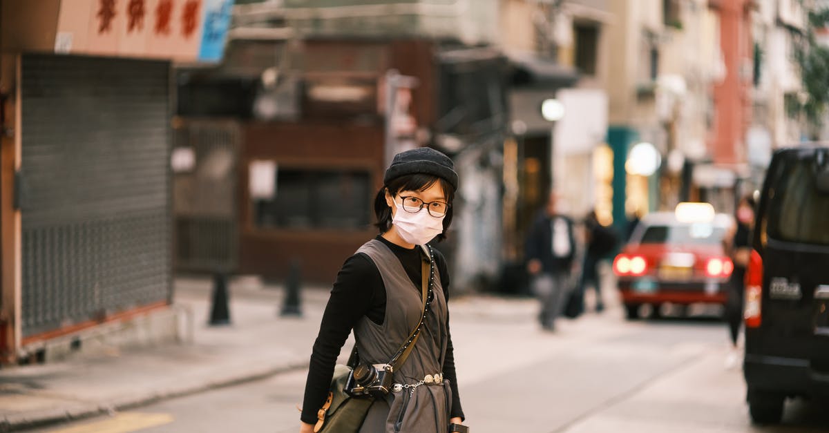 Crossing the Chinese border with a 50cc bike - Asian Woman in Specs and Face Mask Crossing Street in Chinese City