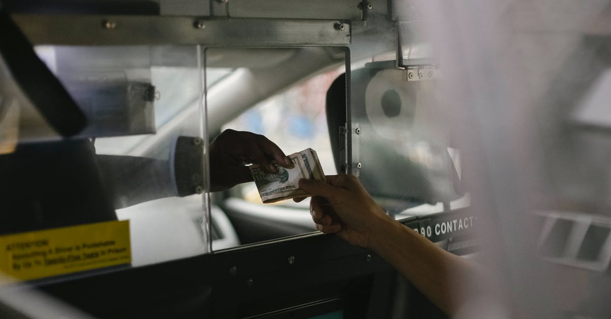 Crossing the US-Canada border by car through visitor visa - View through open window of unrecognizable driver accepting payment in cash from crop customer sitting on back seat