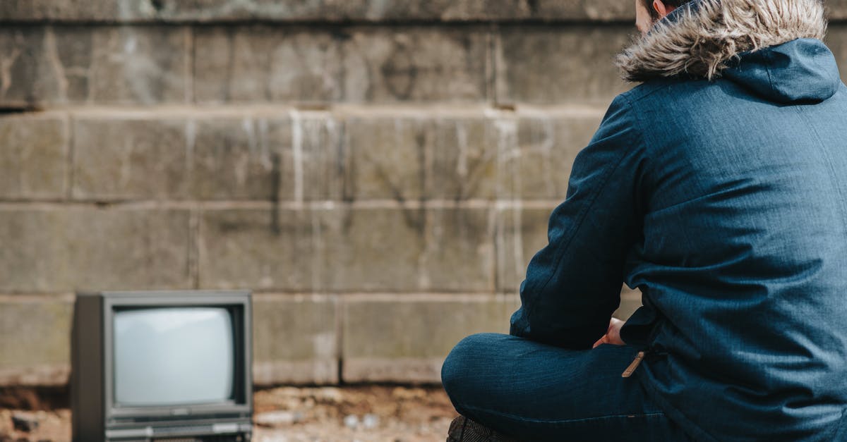 Crossing the US-Canadian border and back - Crop man sitting against vintage TV on street