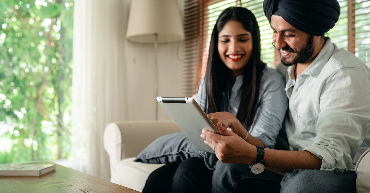 Damaged Indian passport UK visa application [duplicate] - Optimistic ethnic male and female in casual outfit sitting on sofa in living room in daytime and using tablet together