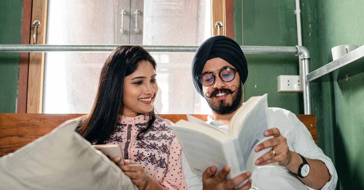 Date of arrival on an Indian e-visa - Smiling couple with book on bed