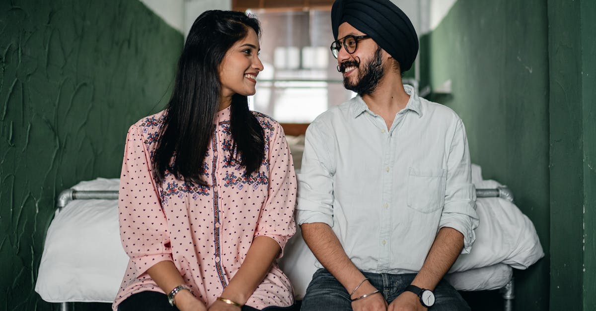 Date of arrival on an Indian e-visa - Happy couple sitting near bed and looking at each other