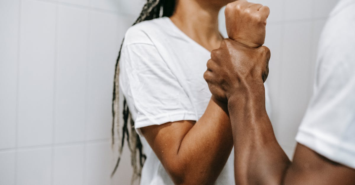 Dealing with aggressive touts in markets? - Side view of crop unrecognizable aggressive African American male holding wrist of scared wife while quarreling together in bathroom