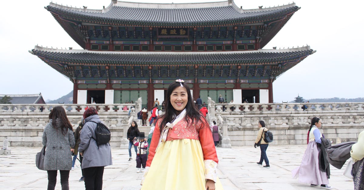 Definition of "first embarkation point" for trip to Indonesia - Positive Asian female tourist wearing long yellow dress standing on square in front of pagoda during vacation