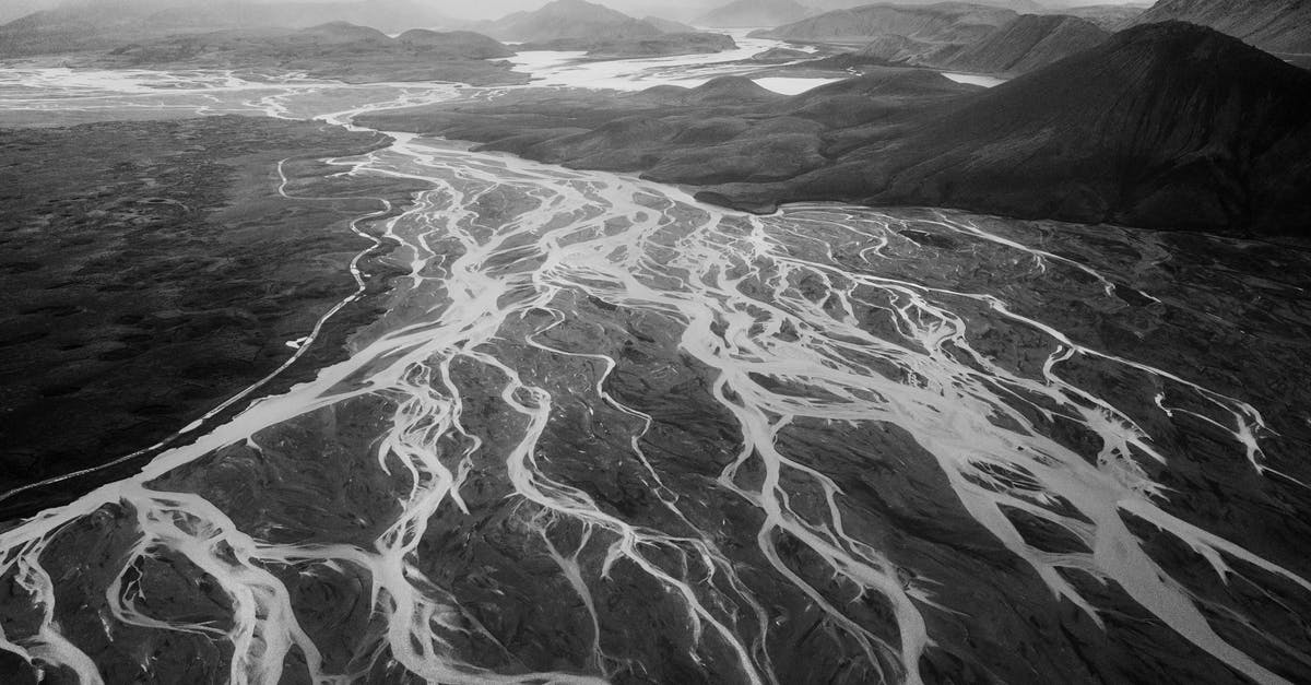 Delta TSA-Precheck status removed - Distance black and white scenery of rough mountainous terrain with breathtaking pattern of glacier frozen rivers under cloudy sky