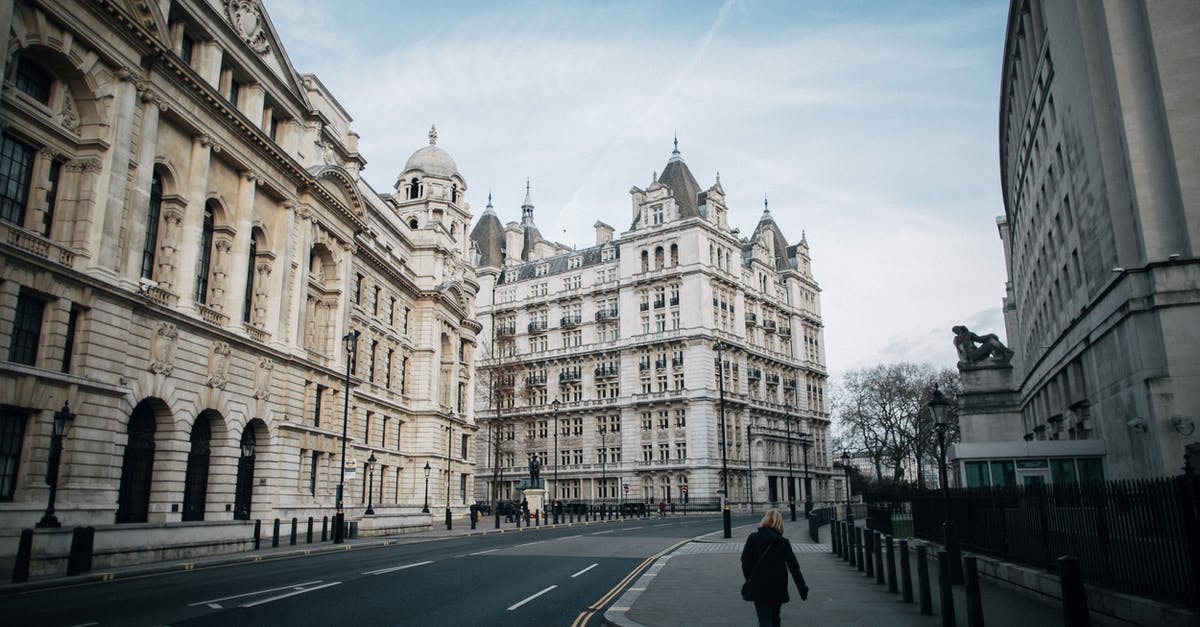 Depart UK by Air or Ship? - Unrecognizable woman walking on pavement between old urban house facades