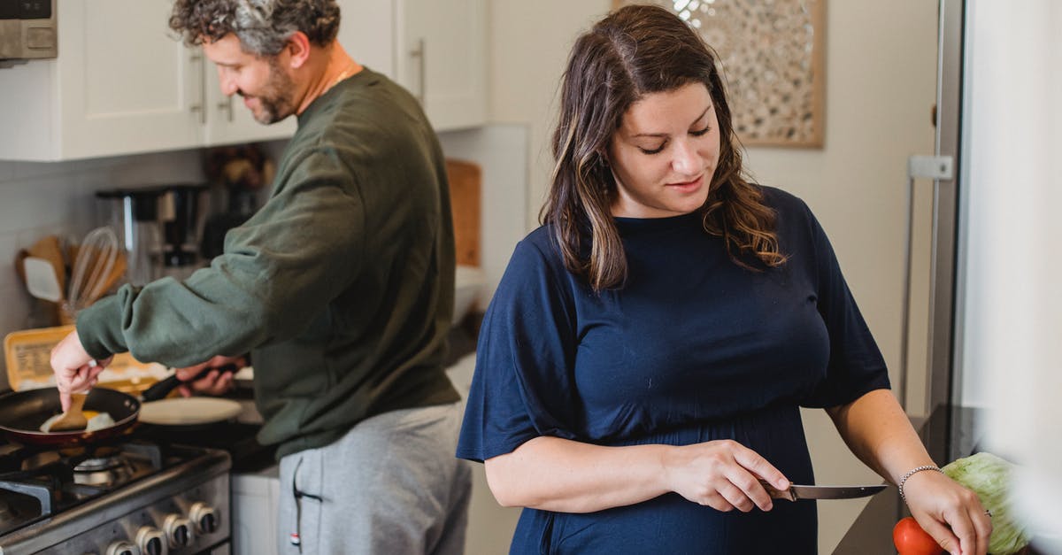 Dependent wife with no marriage certificate: UK visa - Cheerful couple cooking dinner in kitchen