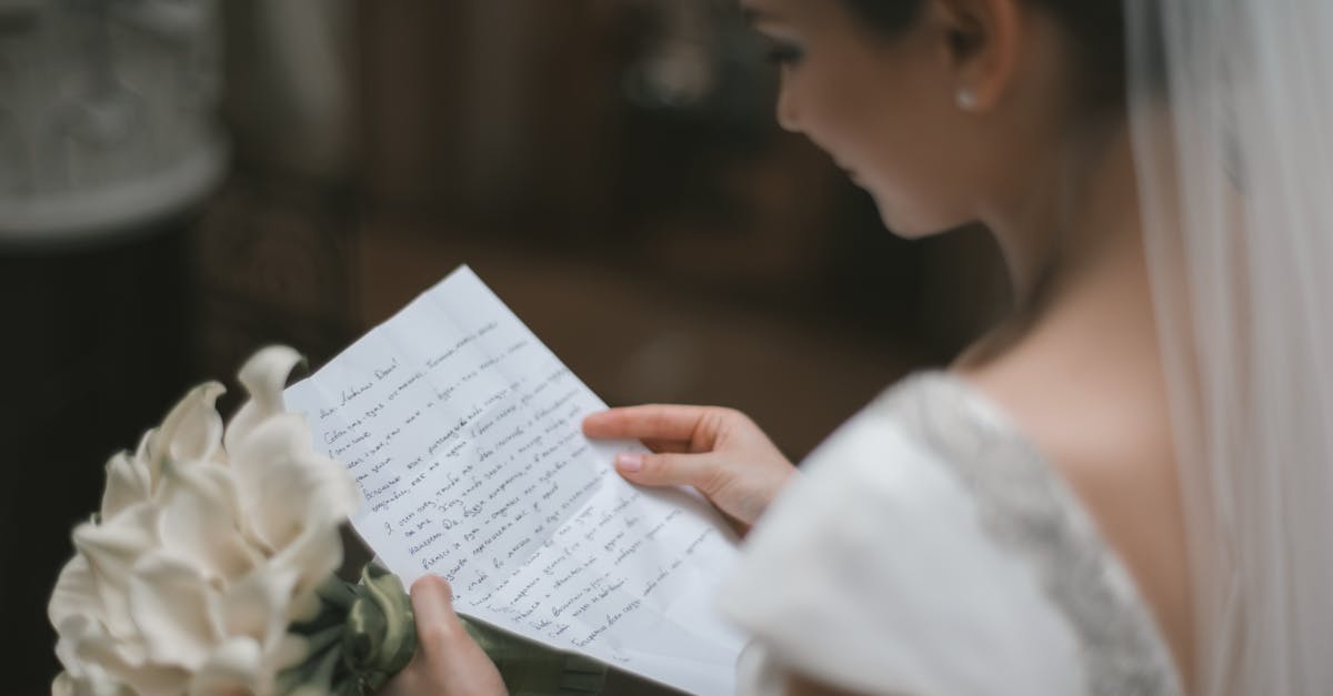 Dependent wife with no marriage certificate: UK visa - Back view of crop charming bride in white dress and veil reading wedding vow on paper sheet with bouquet of arum lilies during weeding ceremony