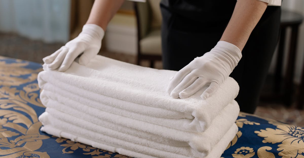 Destroyed sheets and towels in a turkish hotel [closed] - Person Holding a Stack of White Towels