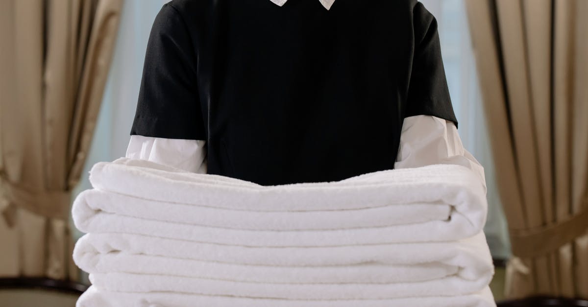 Destroyed sheets and towels in a turkish hotel [closed] - Person Holding a Stack of White Towels