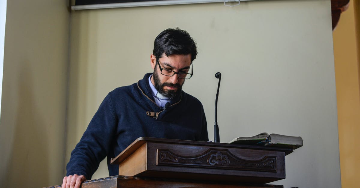 Detailed information about the Habo church - Serious bearded male teacher in casual clothes and eyeglasses reading lecture while standing at wooden podium in conference hall