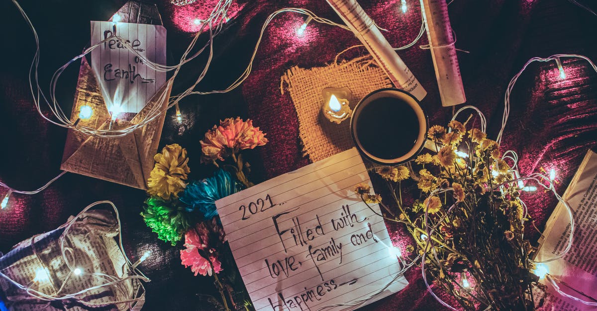 Difference between 'as you wish dining' vs 'second seating' - From above of various Christmas decorations and glowing garland placed on table with paper sheets with different written wishes and cup of coffee