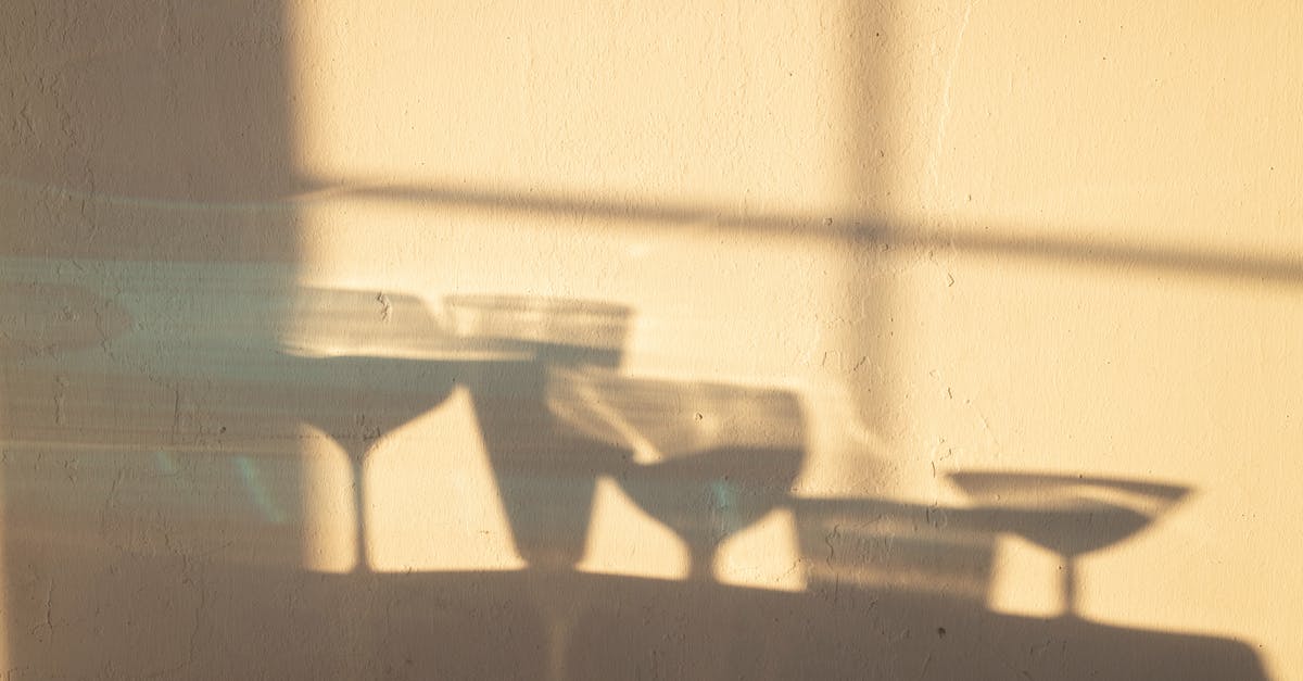 Different liquid restrictions in China and Philippines - Shadows of different crystal glasses filled with drinks reflecting on white wall in sunlight
