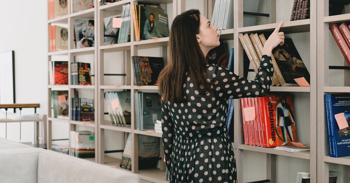 Different surname in university ID and passport - Young woman choosing book from bookshelf