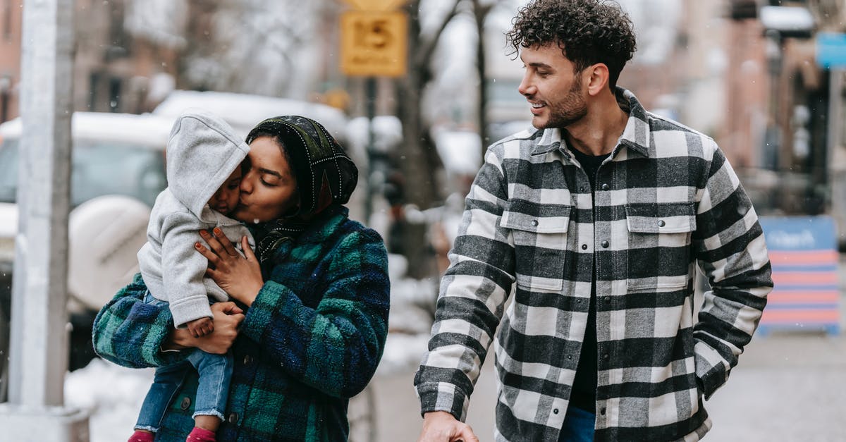 Do airlines count child carriers / baby backpacks as strollers? - Tender multiracial family walking on street with black baby