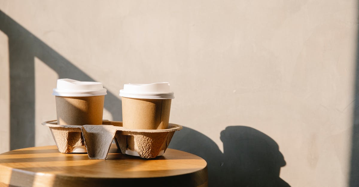 Do All Inland BC Ferries Offer Year Round Service? - Cofee paper cups with plastic lids on holder tray on brown wooden table casting a shadow at sunny day