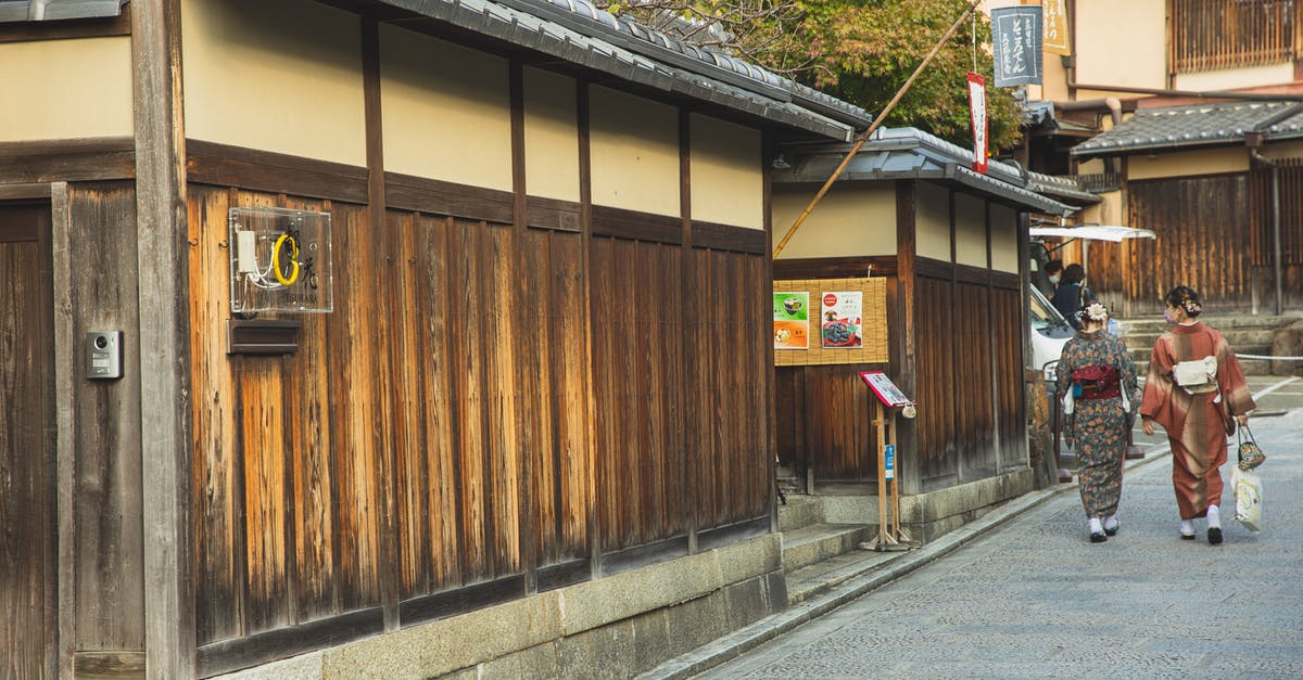 Do any temples or palaces in Japan have a dress code? - Back view of unrecognizable local Japanese ladies in traditional kimonos walking on paved street near typical aged wooden houses in Kyoto