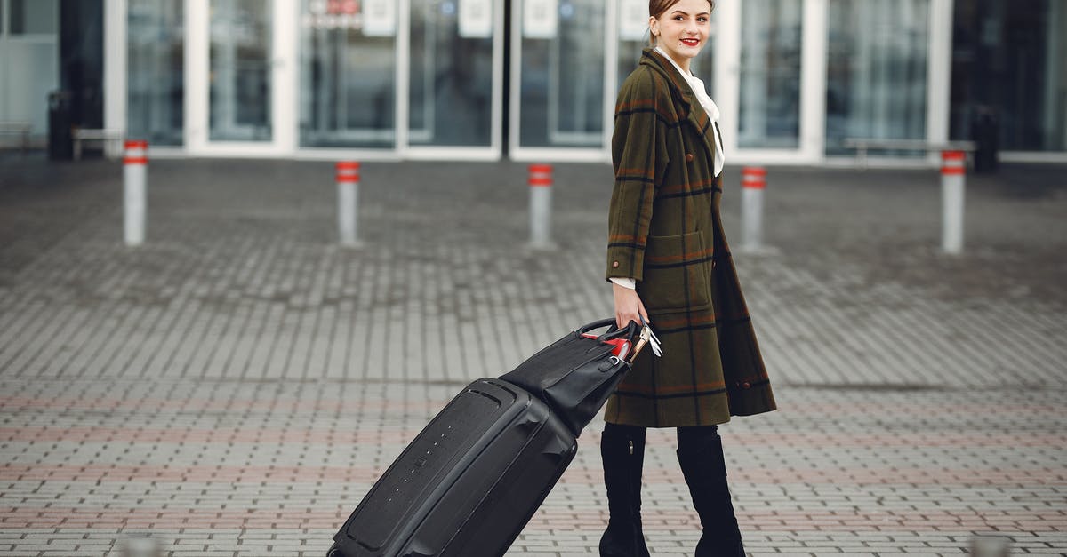 Do baggage cart management units at Toronto Pearson International Airport accept bills and return change? - Full length of smiling female manager in stylish coat walking with suitcase and bag while traveling on business trip smiling away