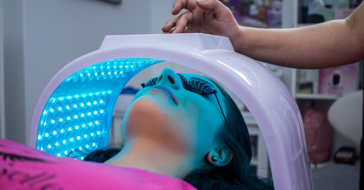 Do ear wax cleaning salons provide related, similar services? - Unrecognizable woman with dark hair with pierced ears lying under ultraviolet lamp while visiting contemporary clinic and spending time in modern salon