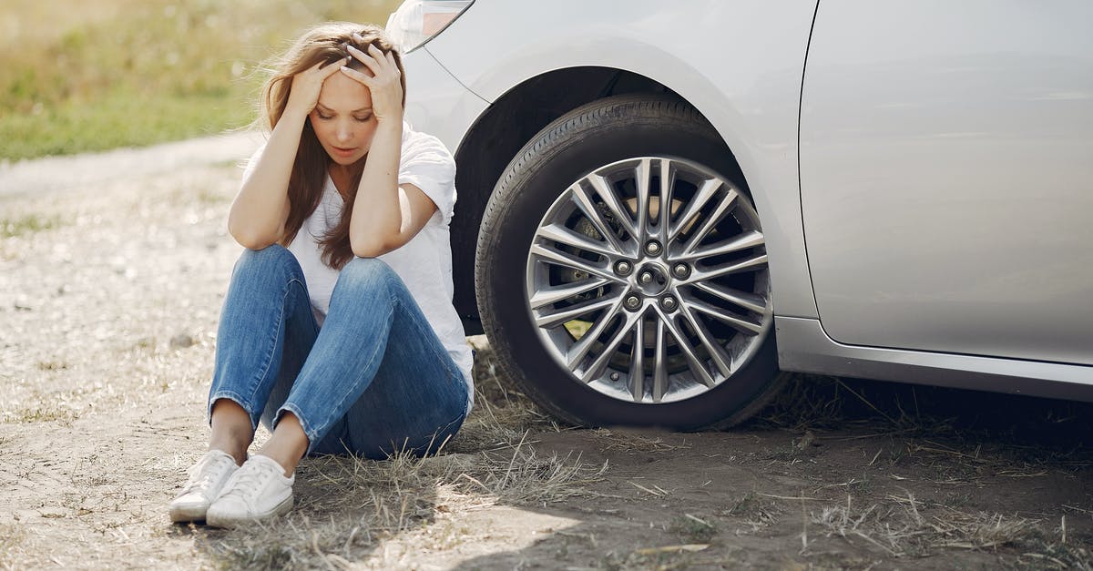 Do EU residents need visa to travel to USA? - Frustrated female driver in white t shirt and jeans sitting on ground near damaged car with hands on head during car travel in sunny summer day