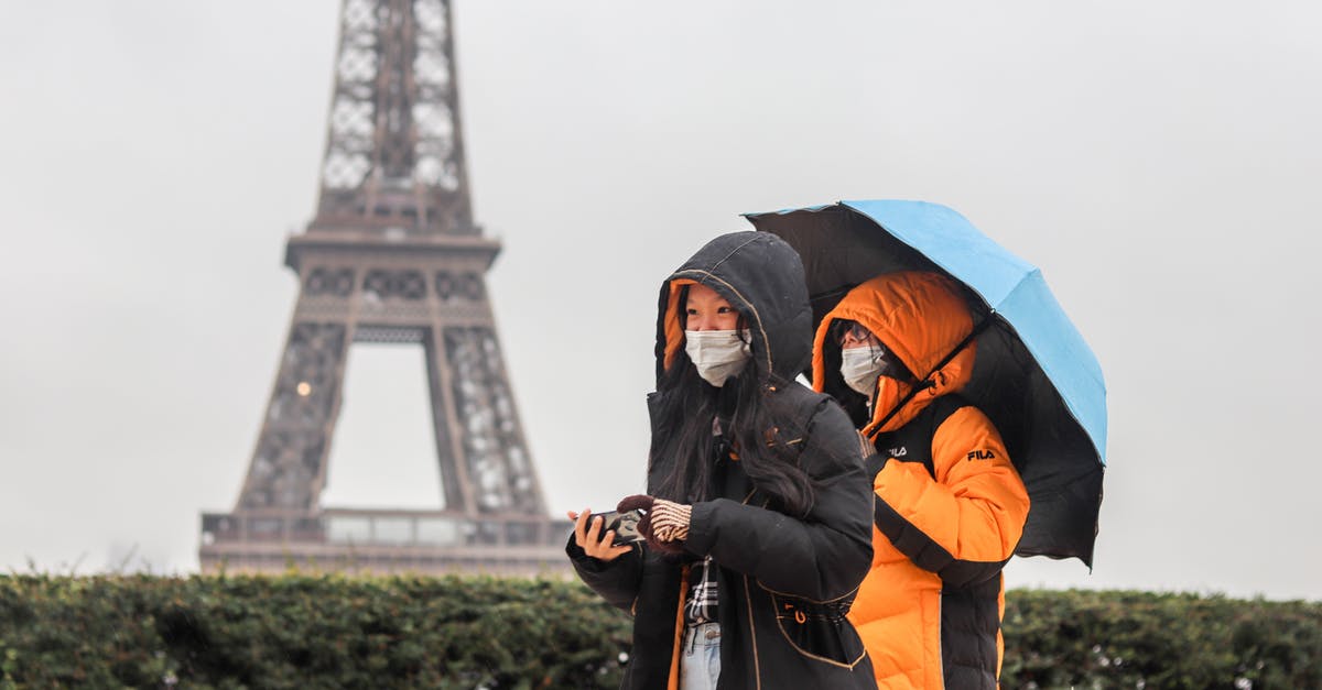 Do F-1 students need a visa to visit Paris and Amsterdam during layovers? [duplicate] - Anonymous ethnic tourists walking along street on foggy rainy day in Paris