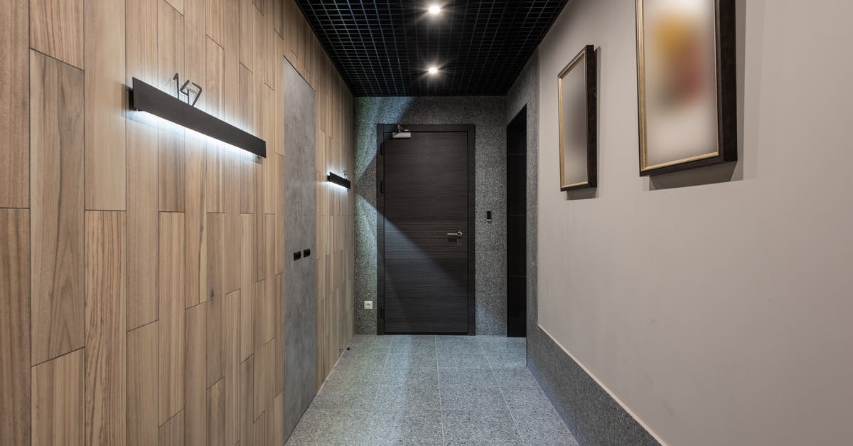 Do Hotel receipts in England show number of guests? - Interior of hallway with illuminated numbers of hotel rooms hanging on wall near doors