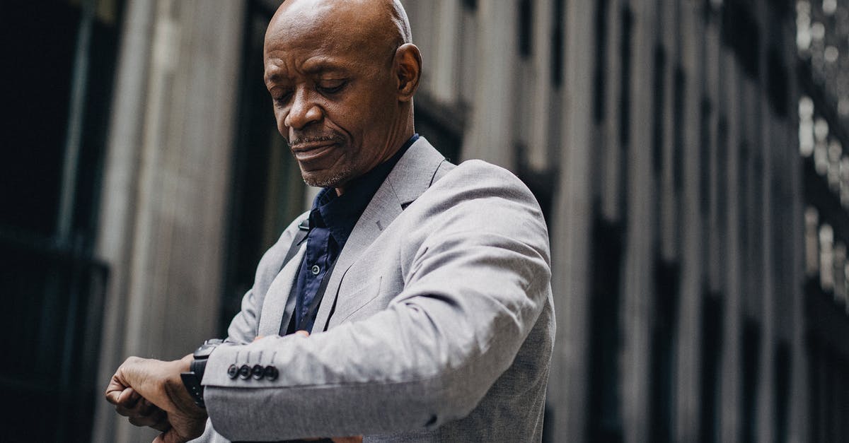 Do I have time to visit downtown London during a 4-hour layover at Heathrow? - Serious African American businessman in formal suit looking at wristwatch while standing outside modern business center building Do I have time to visit downtown London during a 4-hour layover at Heathrow? - Serious African American businessman in formal suit looking at wristwatch while standing outside modern business center building
