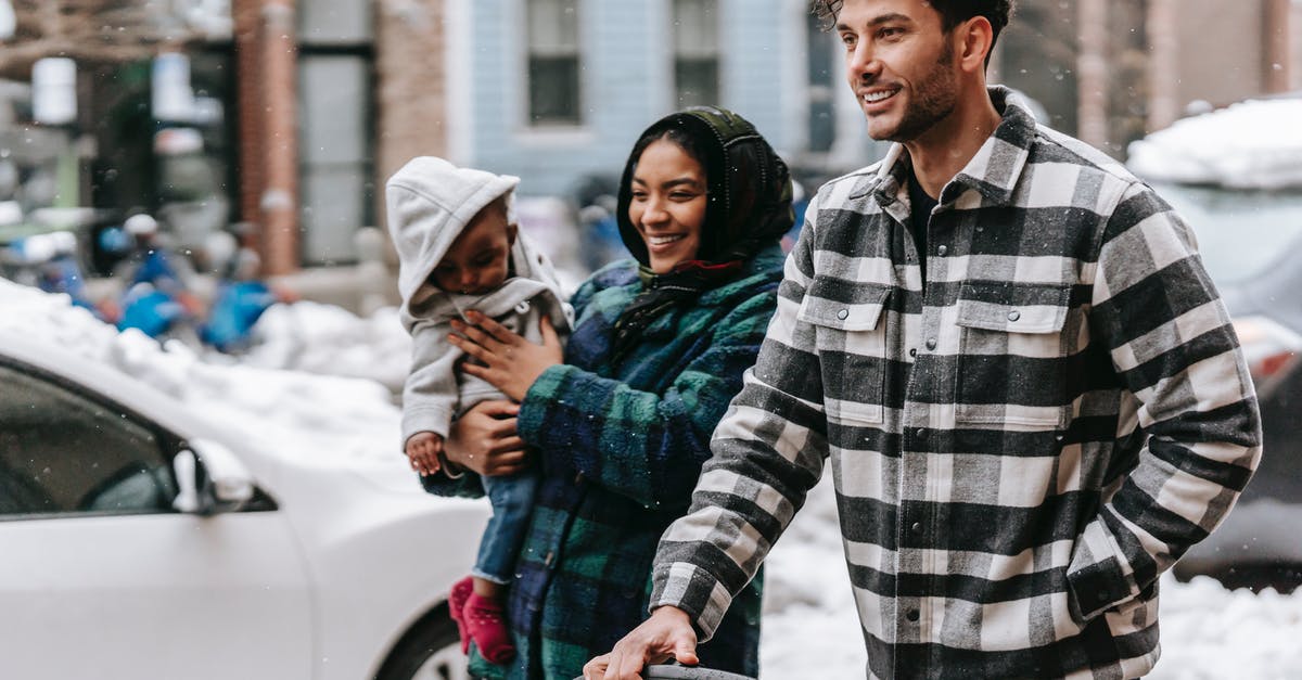 Do I have to carry snow chains in Europe? - Cheerful young diverse family with toddler strolling on street and smiling