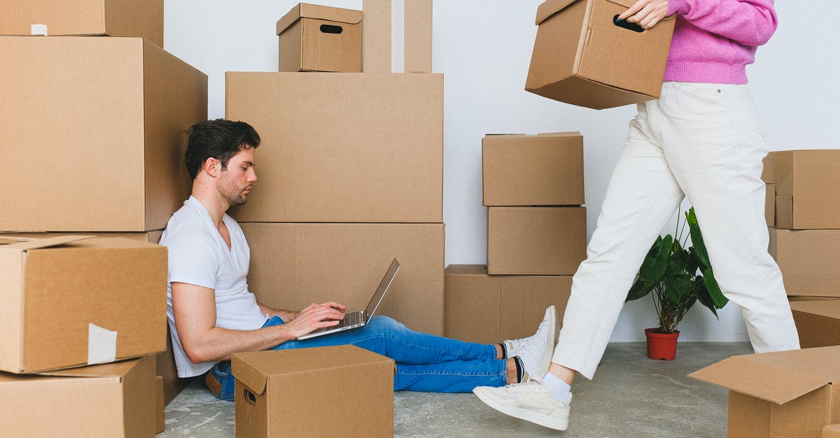 Do I have to declare my new laptop when leaving? - Crop woman arranging carton boxes during relocation with boyfriend using laptop on floor