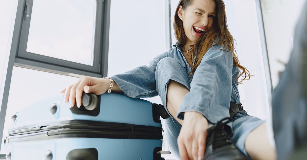 Do I have to recheck my luggage in Chicago? - Low angle of young exited female traveler with suitcase in stylish outfit having fun before flight