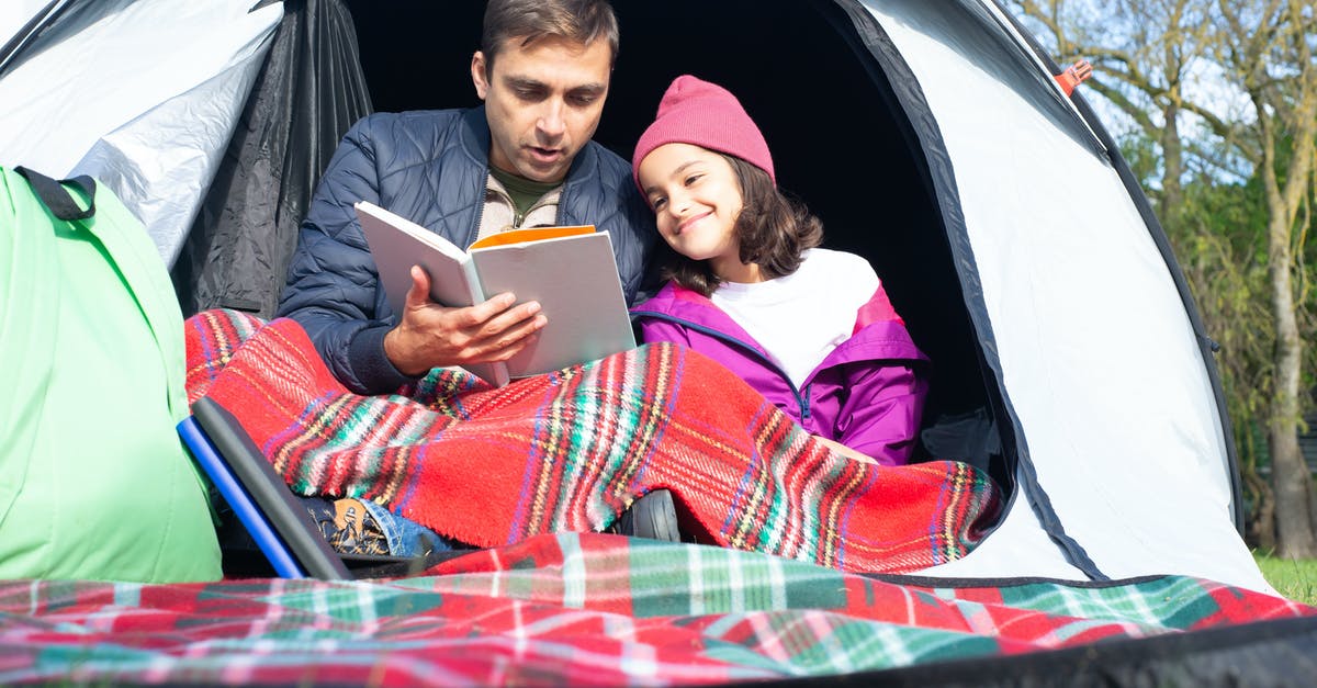 Do I need to book in advance in French camping parks? - Father and Daughter Reading a Book while Sitting Inside the Tent