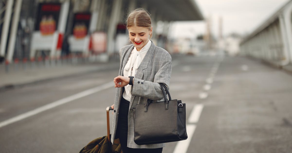 Do I need to re-check my luggage while changing flights in Manchester, UK? - Positive young businesswoman with suitcase hurrying on flight on urban background