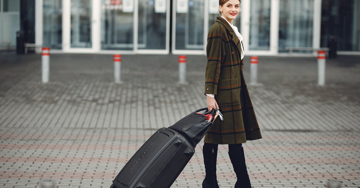 Do internationally arriving passengers see their gate? - Full length of smiling female manager in stylish coat walking with suitcase and bag while traveling on business trip smiling away