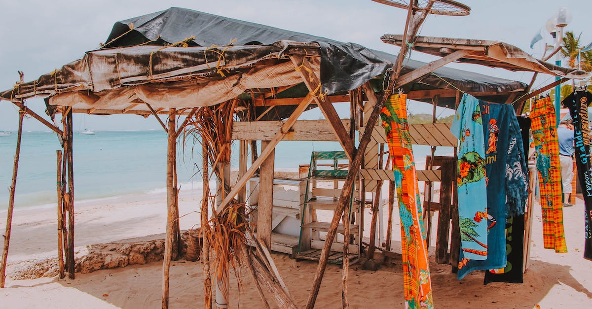 Do microfibre towels dry quicker and absorb more water? - Aged roofed construction made of tree twigs and wooden planks with hanging bright towels on sandy shore near ocean