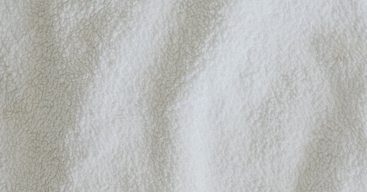 Do microfibre towels dry quicker and absorb more water? - Top view full frame of soft white towel fabric placed on table in light room