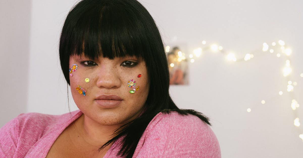 Do NJT buses accept more than exact change? - Tender young ethnic overweight lady with black hair and colourful glitter on face wearing pink shirt standing in light decorated room and looking at camera