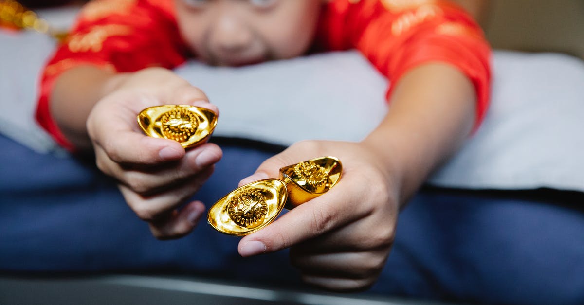 Do NY Metrocards with money ever expire? - Crop happy little Asian boy lying on bed and demonstrating traditional sycee gold ingots during celebration of Chinese New Year