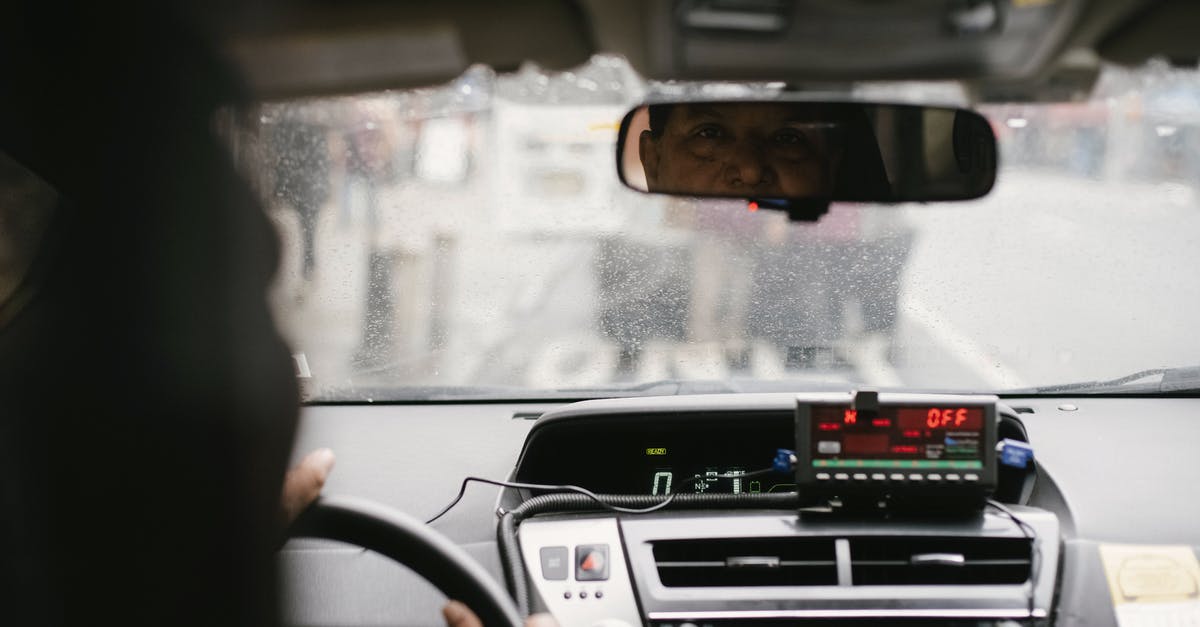 Do pedestrians imitate automotive traffic? - Back view of man reflecting in mirror while driving along street in city on urban background in soft daylight